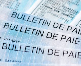 Close-up of several French pay slips ('bulletin de paie'), with some of the many lines of social security contributions and taxes paid by employees and employers in France