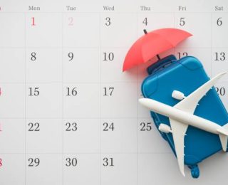 Airplane, suitcase and umbrella on white calendar background. Travel holiday or annual leave travel period for relaxation concept. Period of paid time off (PTO) granted to employees by their employer.