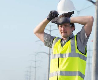 Electrician wipes his forehead after emotional stress on hard work outdoors on power line.