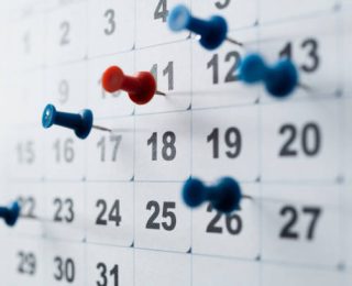 Thumbtack pins on a calendar.